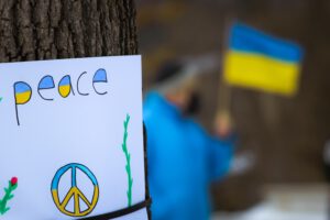 Schild mit Aufschrift "Peace" in den Farben der ukrainischen Flagge